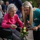 An elderly woman in a wheelchair is assisted by a care-worker as she lays flowers outside Windsor Castle following the death of Queen Elizabeth