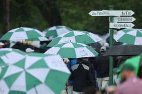 Patrons depart the course under umbrellas after Monday's practice round had been suspended due to a weather warning 