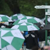 Patrons depart the course under umbrellas after Monday's practice round had been suspended due to a weather warning 