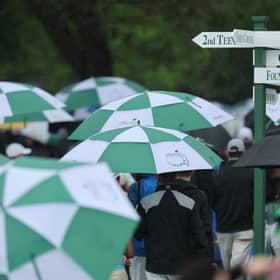Patrons depart the course under umbrellas after Monday's practice round had been suspended due to a weather warning 