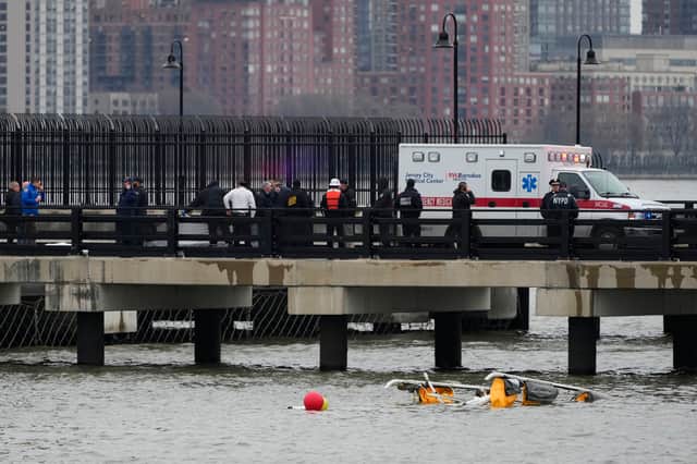 First responders stand on a pier at the scene where a helicopter crashed into the Hudson River