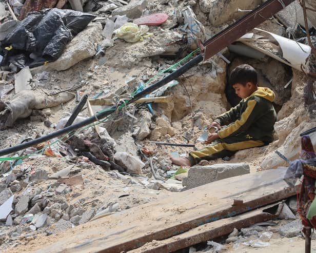 A young Palestinian boy sits amid the debris of a bombed building in Gaza City in March (Picture: Omar Al-Qattaa)