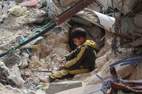 A young Palestinian boy sits amid the debris of a bombed building in Gaza City in March (Picture: Omar Al-Qattaa)