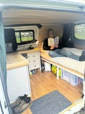 Dom Wright reads inside the back of his converted Ford Transit van