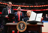 On his first day as US President, Donald Trump holds up an executive order announcing the US's withdrawal from the Paris  climate accord in the Capital One Arena in Washington (Picture: Jim Watson)