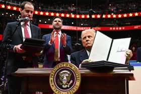 On his first day as US President, Donald Trump holds up an executive order announcing the US's withdrawal from the Paris  climate accord in the Capital One Arena in Washington (Picture: Jim Watson)