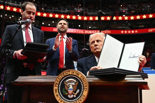 On his first day as US President, Donald Trump holds up an executive order announcing the US's withdrawal from the Paris  climate accord in the Capital One Arena in Washington (Picture: Jim Watson)