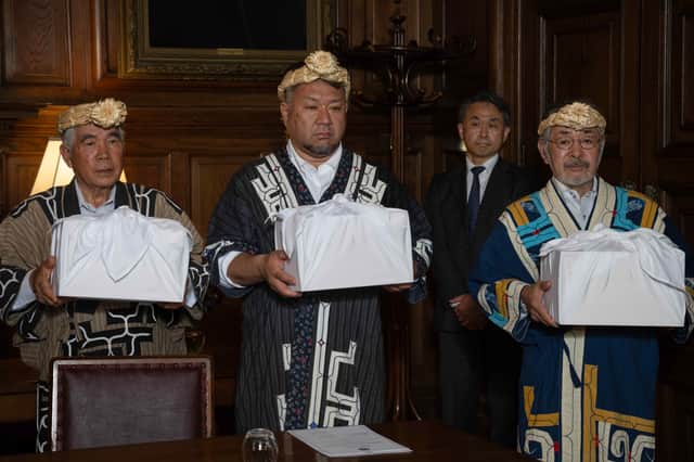 Okawa Masaru, executive director of the Ainu Association of Hokkaido, with Tetsuya Ogawa and Yoshiyuki Uji holding the skulls during the ceremony as the skulls of three indigenous Ainu people were returned to their community by the University of Edinburgh
