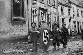 The road to German surrender: Privates H McIvor, W Harton and D Mill from the 10th Highland Light Infantry,15th Scottish Infantry Division, roll a wooden Swastika emblem through Kranenberg during Operation Veritable  on February 10, 1945 at Kranenberg. Scots had a heavy presence in Germany during this period, which led to Operation Plunder and the crossing of the Rhine, the last big set piece ahead of the German surrender.
  British Official Photo B. 14427 (WT). (Photo by Sergeant Norman Midgley/No.5 Army Film & Photographic Unit/BIPPA/Keystone/Hulton Archive/Getty Images).