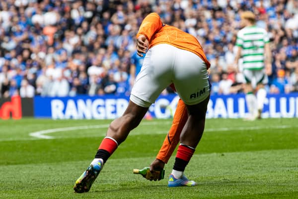 Rangers' Neraysho Kasanwirjo removes a glass bottle from the Ibrox surface.