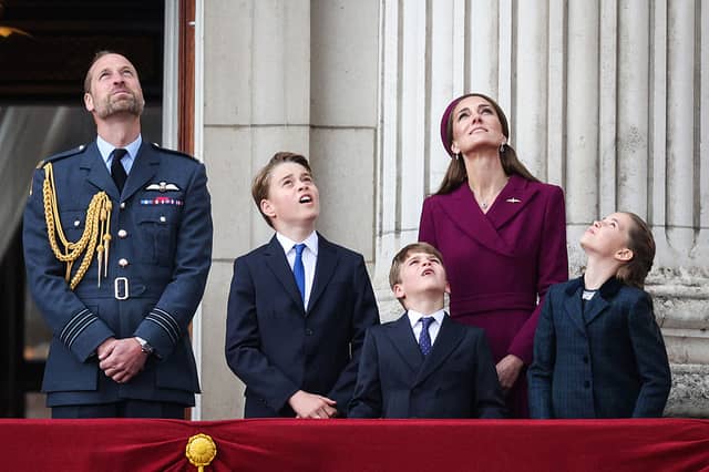 Prince William, Prince of Wales, Prince George of Wales, Prince Louis of Wales, Catherine, Princess of Wales and Princess Charlotte of Wales watch the Red Arrows flypast from Buckingham Palace.