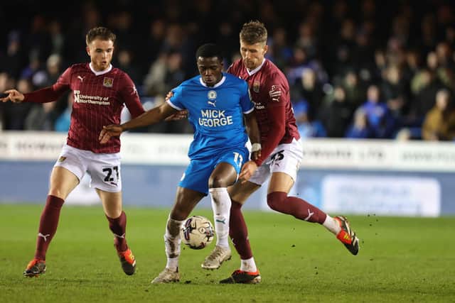 Kwame Poku of Peterborough United attempts to control the ball under pressure from Patrick Brough as Marc Leonard looks on during the Sky Bet League One match between Peterborough United and Northampton Town.