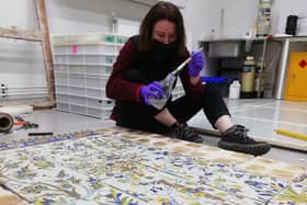 Experts work on restoring the tile painting.