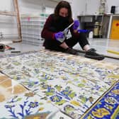 Experts work on restoring the tile painting.