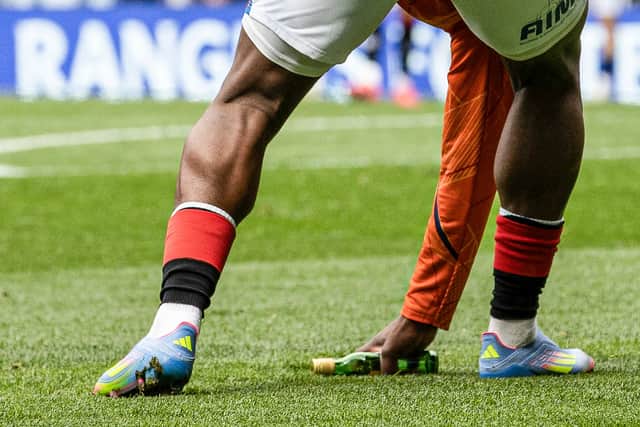 Rangers substitute Neraysho Kasanwirjo removes items from the pitch which were thrown by fans at Celtic's Viljami Sinisalo. (Photo by Alan Harvey / SNS Group)
