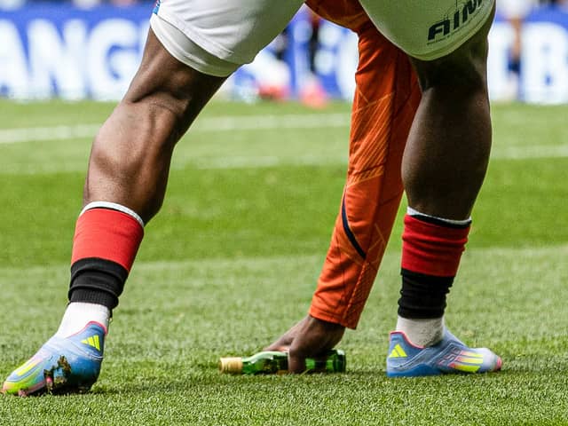 Rangers substitute Neraysho Kasanwirjo removes items from the pitch which were thrown by fans at Celtic's Viljami Sinisalo. (Photo by Alan Harvey / SNS Group)