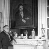 At her apartment in Paris, Gertrude Stein (1874-1946) poses in front of the portrait of her painted by Pablo Picasso in 1906 