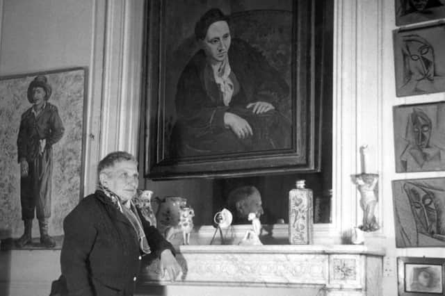 At her apartment in Paris, Gertrude Stein (1874-1946) poses in front of the portrait of her painted by Pablo Picasso in 1906