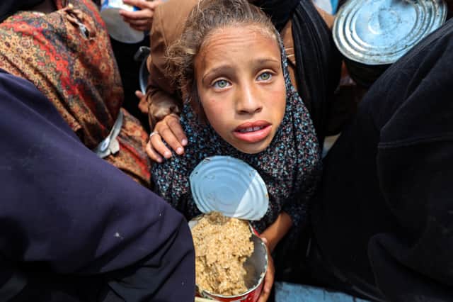 A girl holds a container at a food distribution point in the Nuseirat camp for refugees in central Gaza Strip (Picture: Eyad Baba)