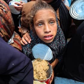 A girl holds a container at a food distribution point in the Nuseirat camp for refugees in central Gaza Strip (Picture: Eyad Baba)