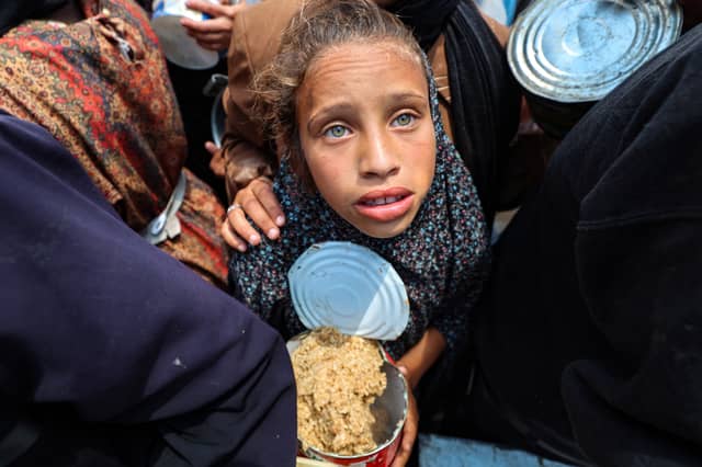 A girl holds a container at a food distribution point in the Nuseirat camp for refugees in central Gaza Strip (Picture: Eyad Baba)