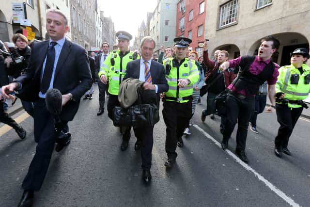 Nigel Farage (centre) on the Royal Mile being escorted by police officers as he leaves the Canons' Gait pub in 2013, while Ukip leader. Protestors heckled him during his visit to Edinburgh.