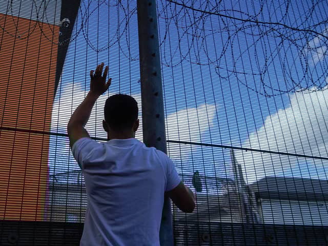 A protester communicates with people held inside the Brook House Immigration Removal Centre near Gatwick Airport (Picture:  Niklas Halle'n)