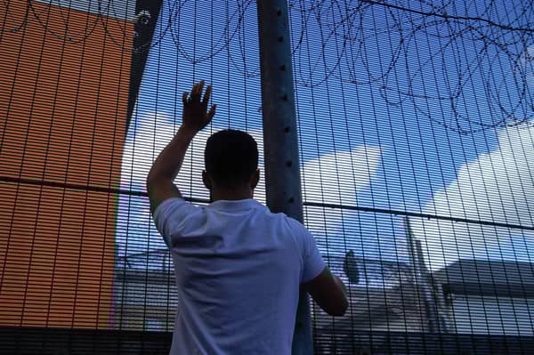 A protester communicates with people held inside the Brook House Immigration Removal Centre near Gatwick Airport (Picture:  Niklas Halle'n)