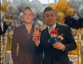 Hiroshi Suzuki trying Irn Bru next to a cardboard cutout of Robbie Williams, who is playing Murrayfield this weekend.
