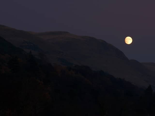 The full moon rising above hills in Scotland