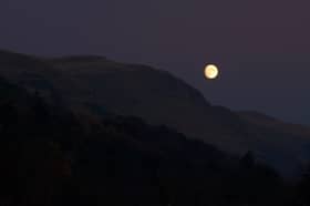 The full moon rising above hills in Scotland