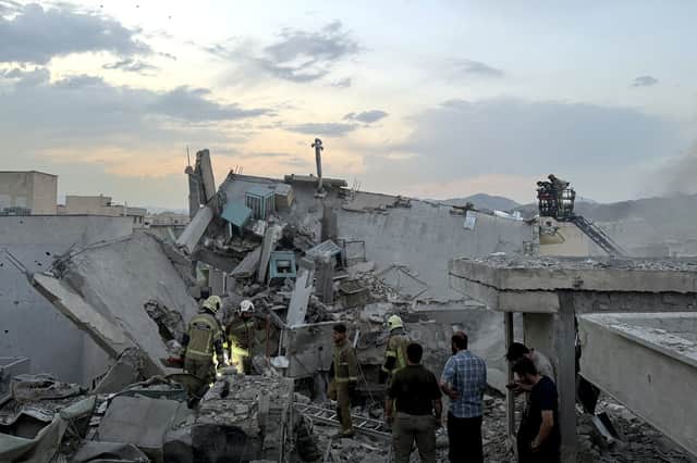 People and first-responders gather atop a building that was hit by an Israeli strike in Tehran