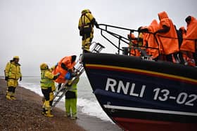 Migrants, picked up at sea attempting to cross the English Channel, are helped ashore from an Royal National Lifeboat Institution (RNLI) lifeboat, at Dungeness on the southeast coast of England, on December 9, 2022