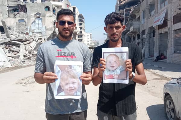 Two men in Gaza hold photographs of two-year-old Omer Siman Tov and nine-month-old Kfir Bibas, who both died as a result of the October 7 attack on Israeli by Hamas