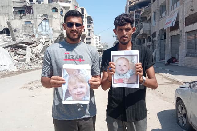 Two men in Gaza hold photographs of two-year-old Omer Siman Tov and nine-month-old Kfir Bibas, who both died as a result of the October 7 attack on Israeli by Hamas