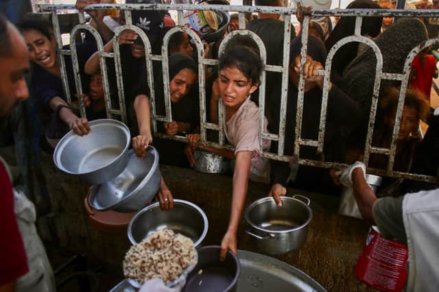 Palestinians queue to receive food at a charity kitchen in Khan Yunis in the southern Gaza Strip on Tuesday