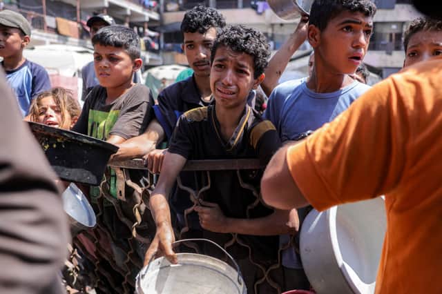 A boy, clearly in distress, queues for food in a charity kitchen in Gaza City earlier this month (Picture: Bashar Taleb)