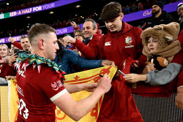 Scotland's Finn Russell signs a flag after the Lions overcame Australia.