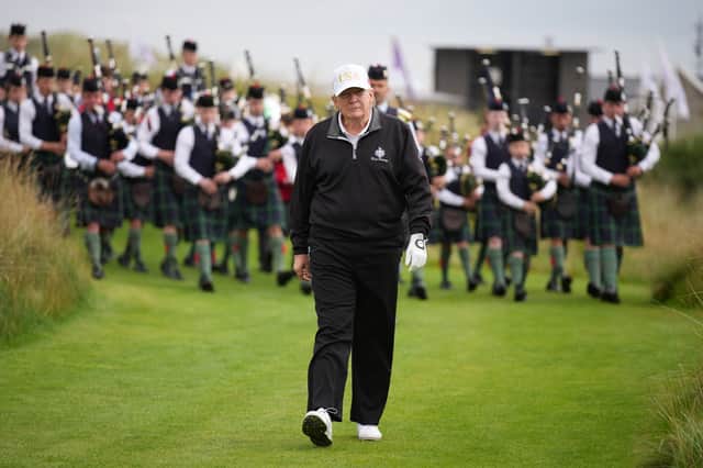 US President Donald Trump walks on the course followed by a pipe band at the ribbon-cutting ceremony of a new course at Trump International Golf Links in Balmedie near Aberdeen