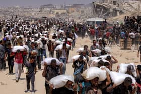 Scores of people carry sacks of flour through the ruins of northern Gaza. UN-backed food security experts have warned the 'worst-case scenario of famine' is playing out in the area (Picture: Bashar Taleb)