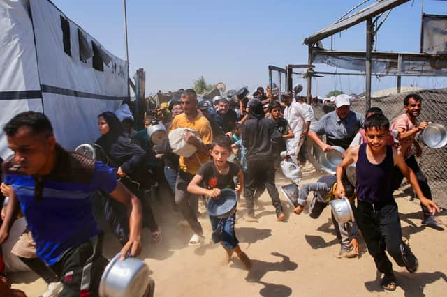 People rush to join a queue at a charity kitchen in Khan Yunis in the southern Gaza Strip