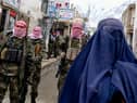 Taliban fighters watch as a woman walks in a market in the Baharak district of Badakhshan province (Picture: Wakil Kohsar)