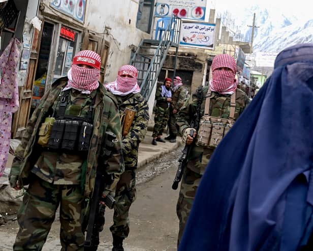 Taliban fighters watch as a woman walks in a market in the Baharak district of Badakhshan province (Picture: Wakil Kohsar)