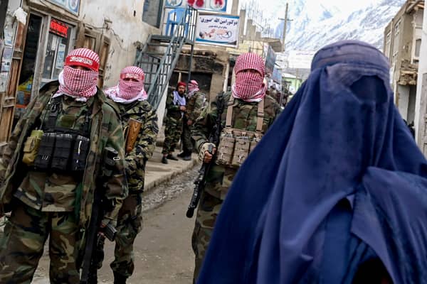 Taliban fighters watch as a woman walks in a market in the Baharak district of Badakhshan province (Picture: Wakil Kohsar)