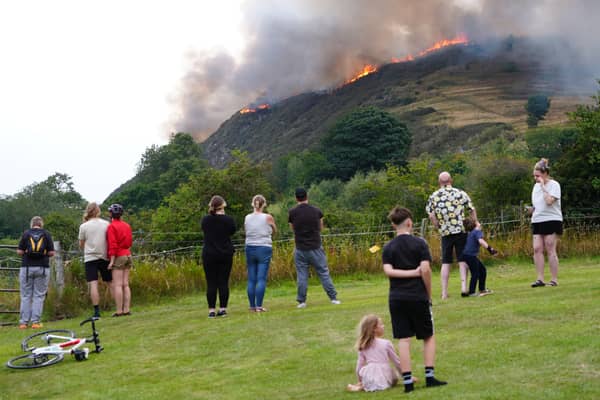 Members of the public stand back and watch flames rip through Arthur's Seat. 