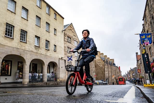 Alastair Dalton riding a Voi Explorer Light 1 over the tarmac of Canongate in Edinburgh - altogether more pleasant than cycling on setts