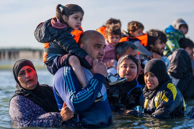 A girl sits on a man's shoulders as they and others prepare to board a dinghy near Gravelines, France, on the English Channel coast (Picture: Carl Court)