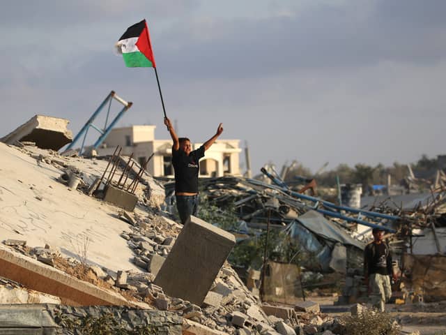 A child waves a Palestinian flag as he stands on the rubble of a destroyed building at the Bureij camp for refugees in the central Gaza Strip on Monday (Picture: Eyad Baba)