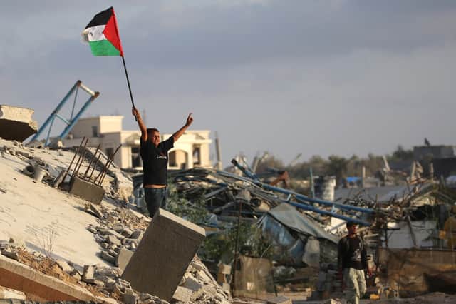 A child waves a Palestinian flag as he stands on the rubble of a destroyed building at the Bureij camp for refugees in the central Gaza Strip on Monday (Picture: Eyad Baba)