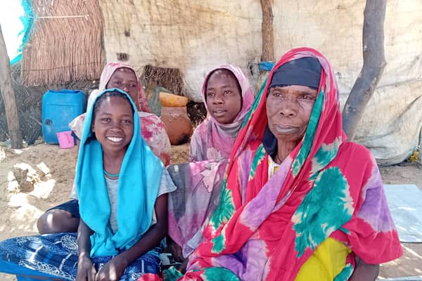 Naima and her daughters sit in the shade of the temporary shelter that is their home in Zabout camp.